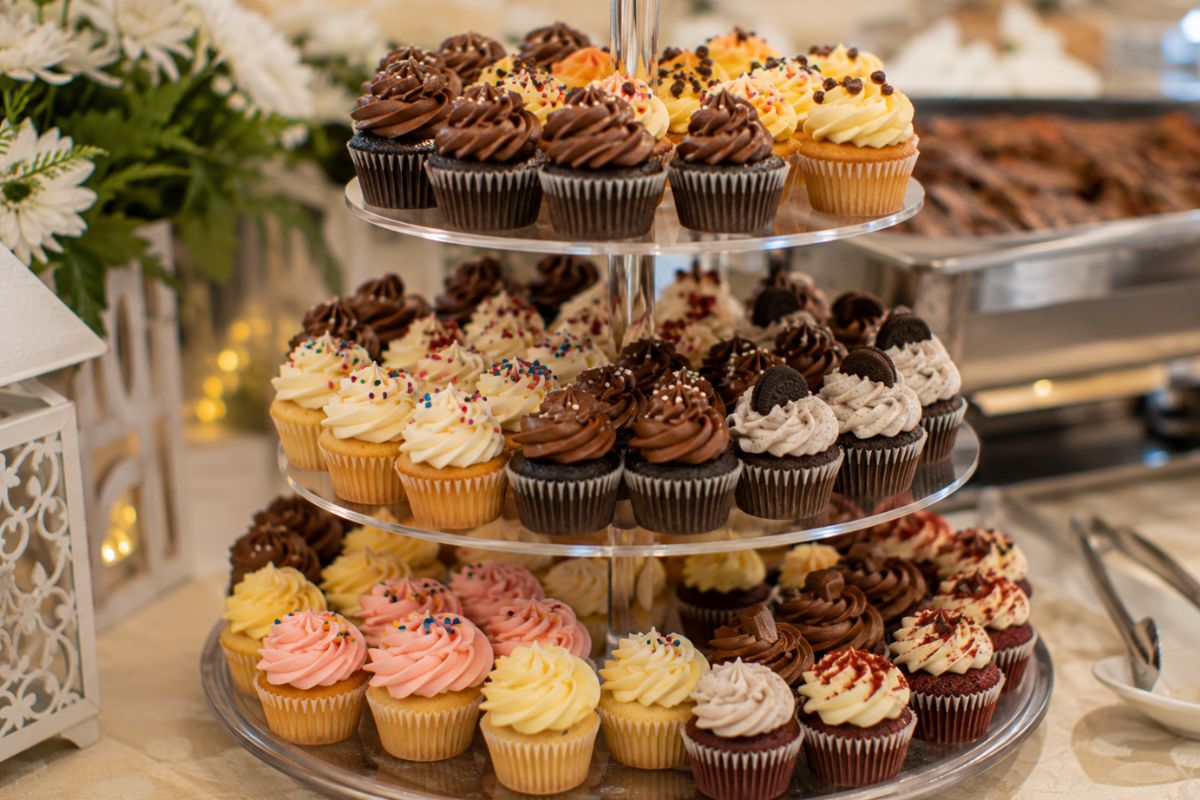 Assorted wedding cupcakes with chocolate, vanilla, and red velvet flavors displayed on elegant tiered stands, offering an affordable and beautifully presented dessert option for a wedding reception.