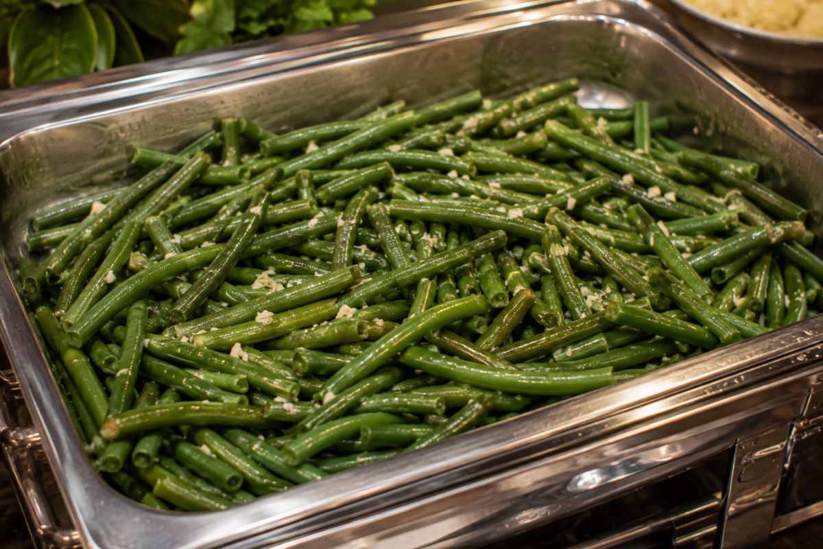 Garlic green beans sautéed with olive oil and minced garlic, served in a stainless steel buffet chafing dish as a fresh and budget-friendly side dish for a wedding reception.
