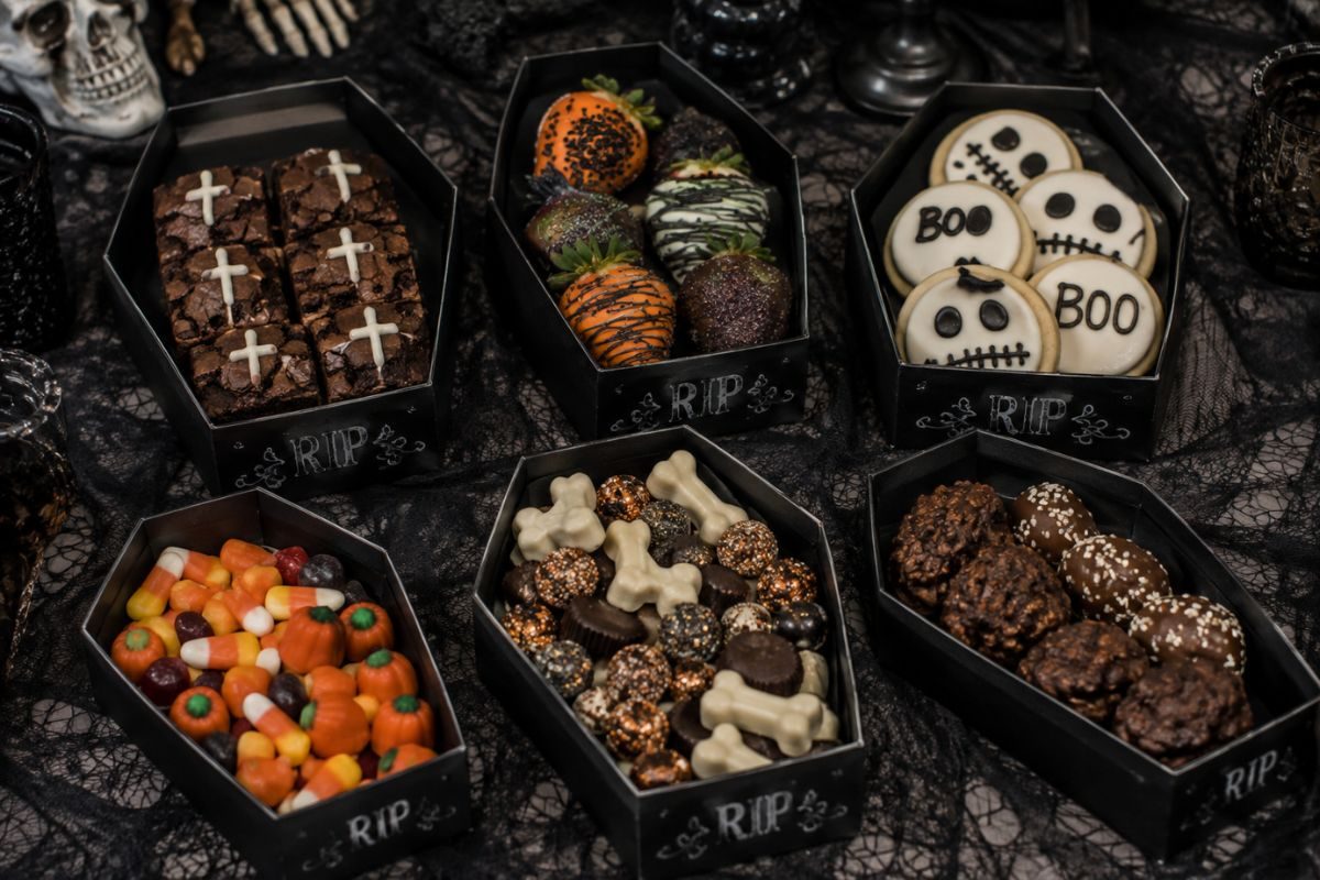 Coffin-shaped Halloween dessert boxes filled with brownies, chocolate-covered strawberries, spooky cookies, candy, and assorted sweet treats.