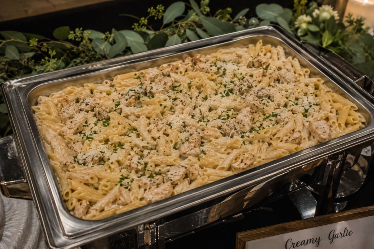 Creamy garlic chicken penne served in a buffet chafing dish, topped w
