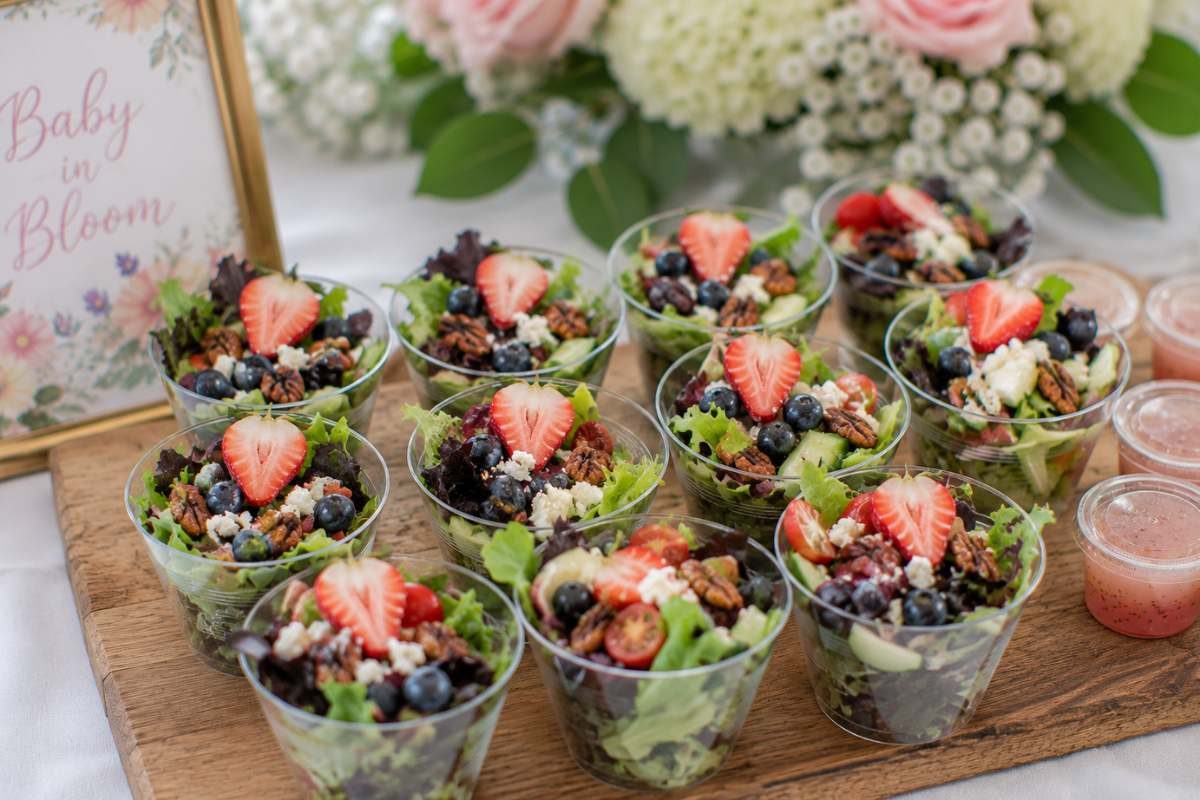 Individual salad cups layered with mixed greens, berries, cucumbers, feta cheese, and candied pecans for an elegant baby shower appetizer.