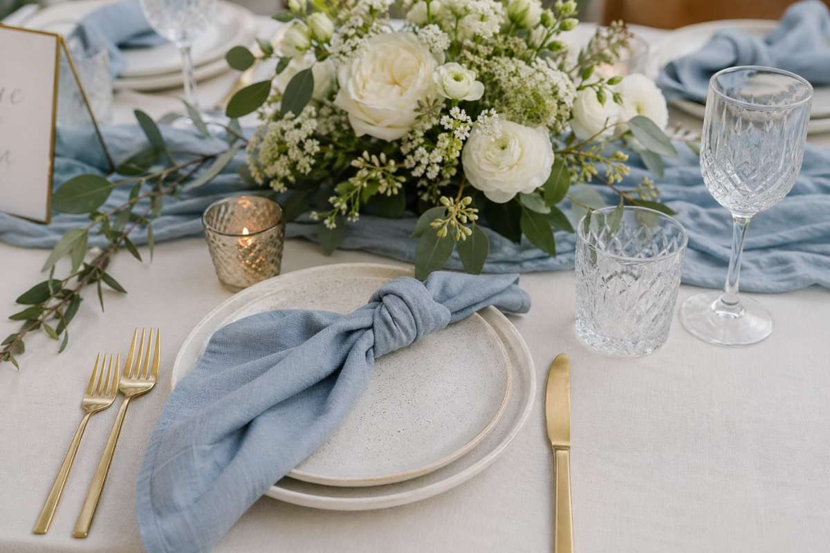 dusty blue knotted napkin with floral centerpiece and glassware