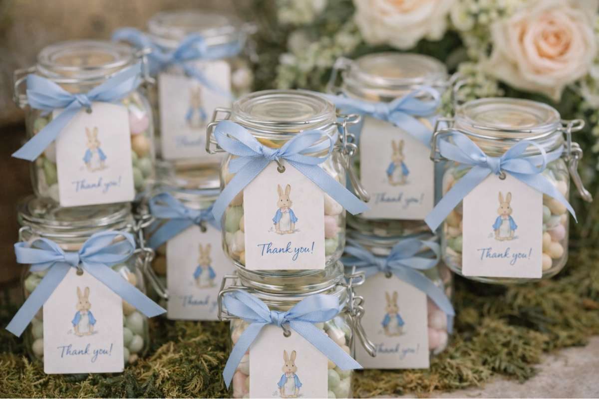 Glass jars with pastel candies and blue ribbon tags for baby shower favors
